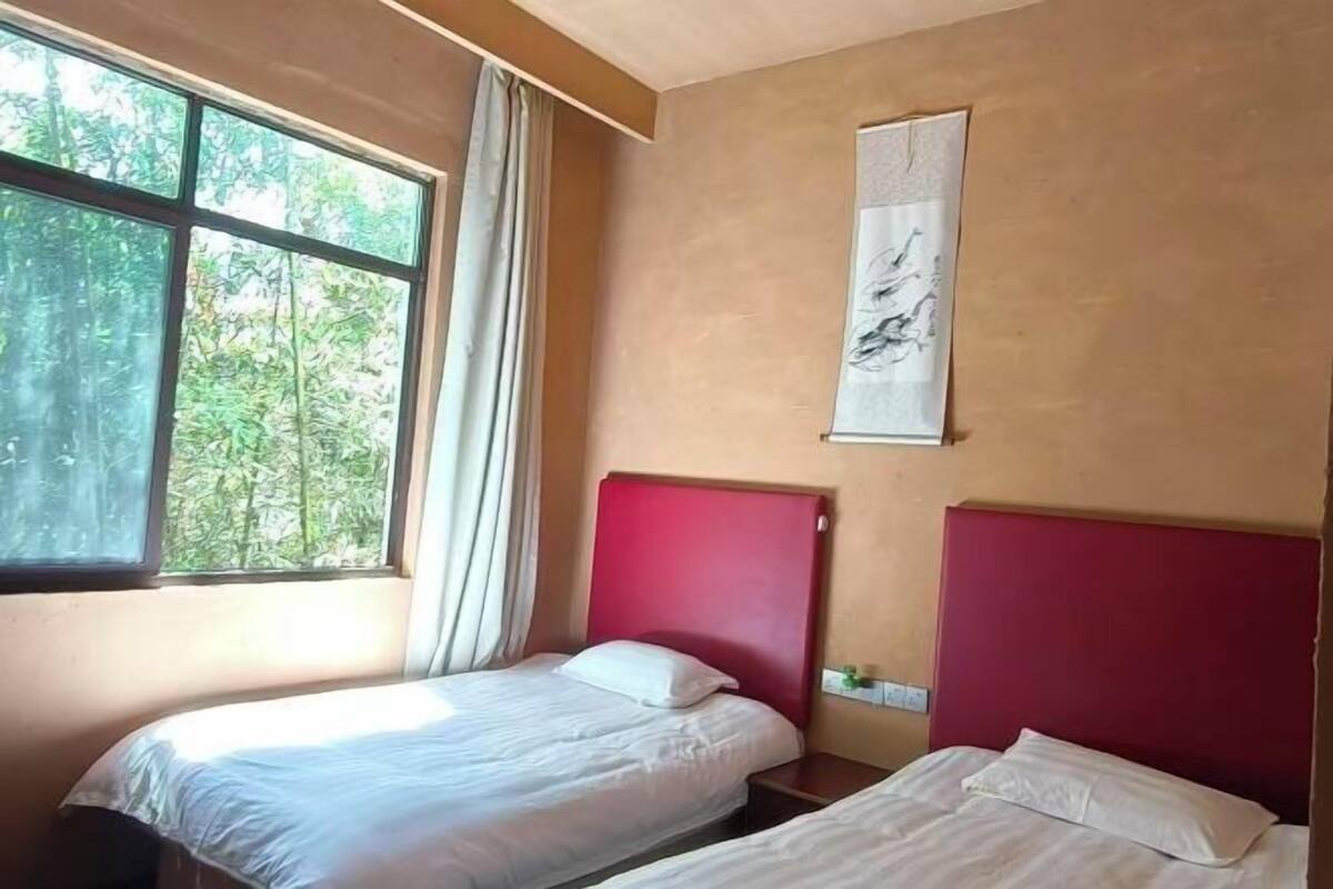 Une chambre avec deux lits, une fenêtre avec des rideaux et une œuvre d’art accrochée au mur.