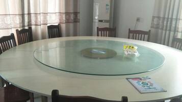 A round glass table with chairs around it, a whiteboard, and a window with curtains.