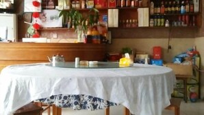 Ein runder Tisch mit weißer Tischdecke und Blumenmuster, umgeben von Holzstühlen.