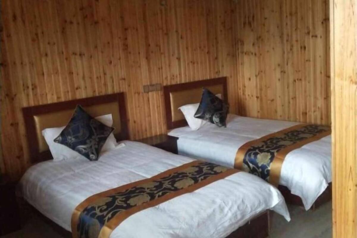 Deux lits simples avec des têtes de lit en bois, une literie blanche et des coussins décoratifs.