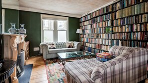 Una sala de estar acogedora con chimenea, un sofá, una mesa de centro y una estantería llena de libros.
