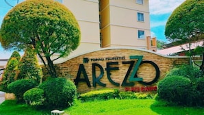 A sign for 'Paimma Properties Arezo Place Davac' with a stone wall and greenery. - Lian's Haven at Arezzo Place Davao (Davao City)