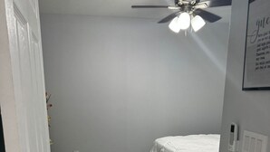 Een slaapkamer met een bed, een plafondventilator en een marmeren vloer.
