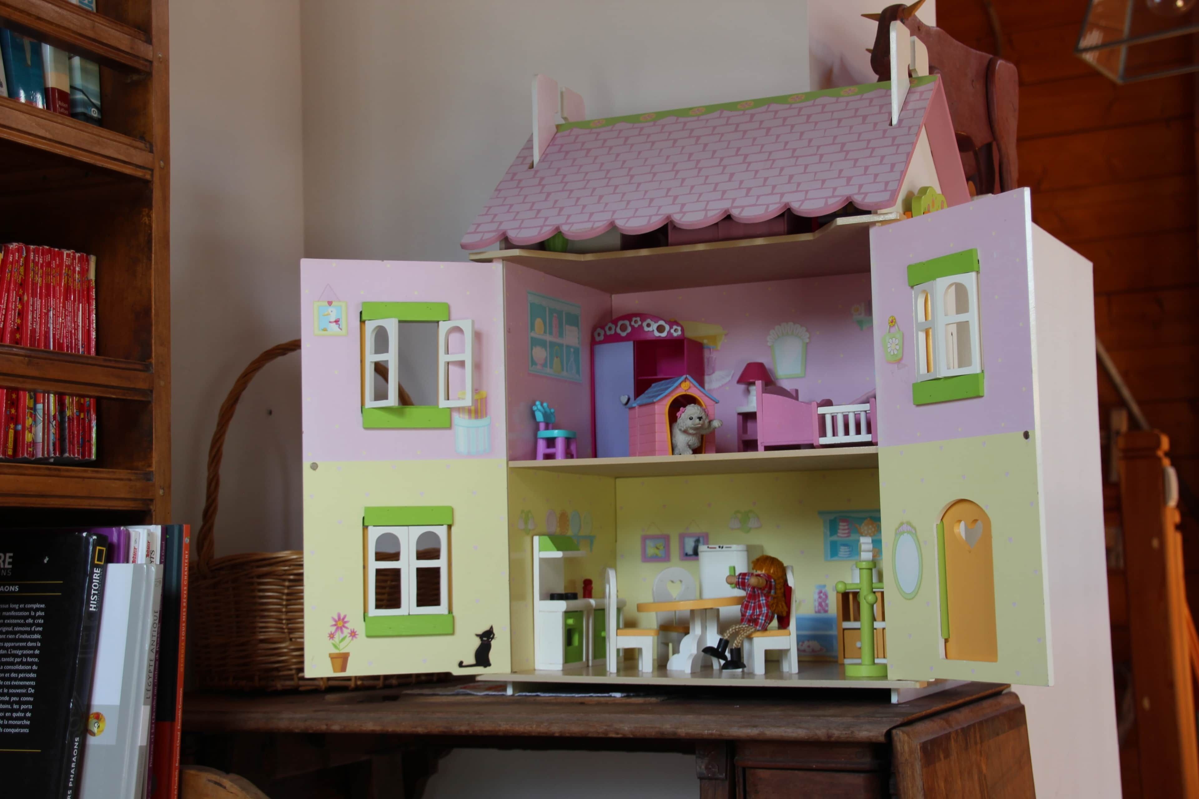 Ein Puppenhaus mit zwei Etagen, jede mit unterschiedlichen Räumen und Möbeln.