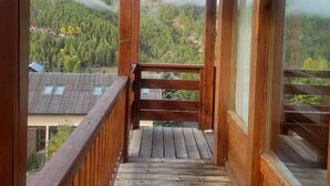 A wooden balcony with a view of a forested mountain range. - Chalet face aux étoiles (Molines-en-Queyras)