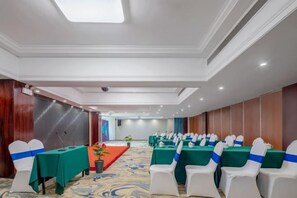 A conference room with rows of white chairs, green tables, and a stage area. - Kameidun Hotel (Changsha University of Science and Technology Yuntang Campus) (Changsha)