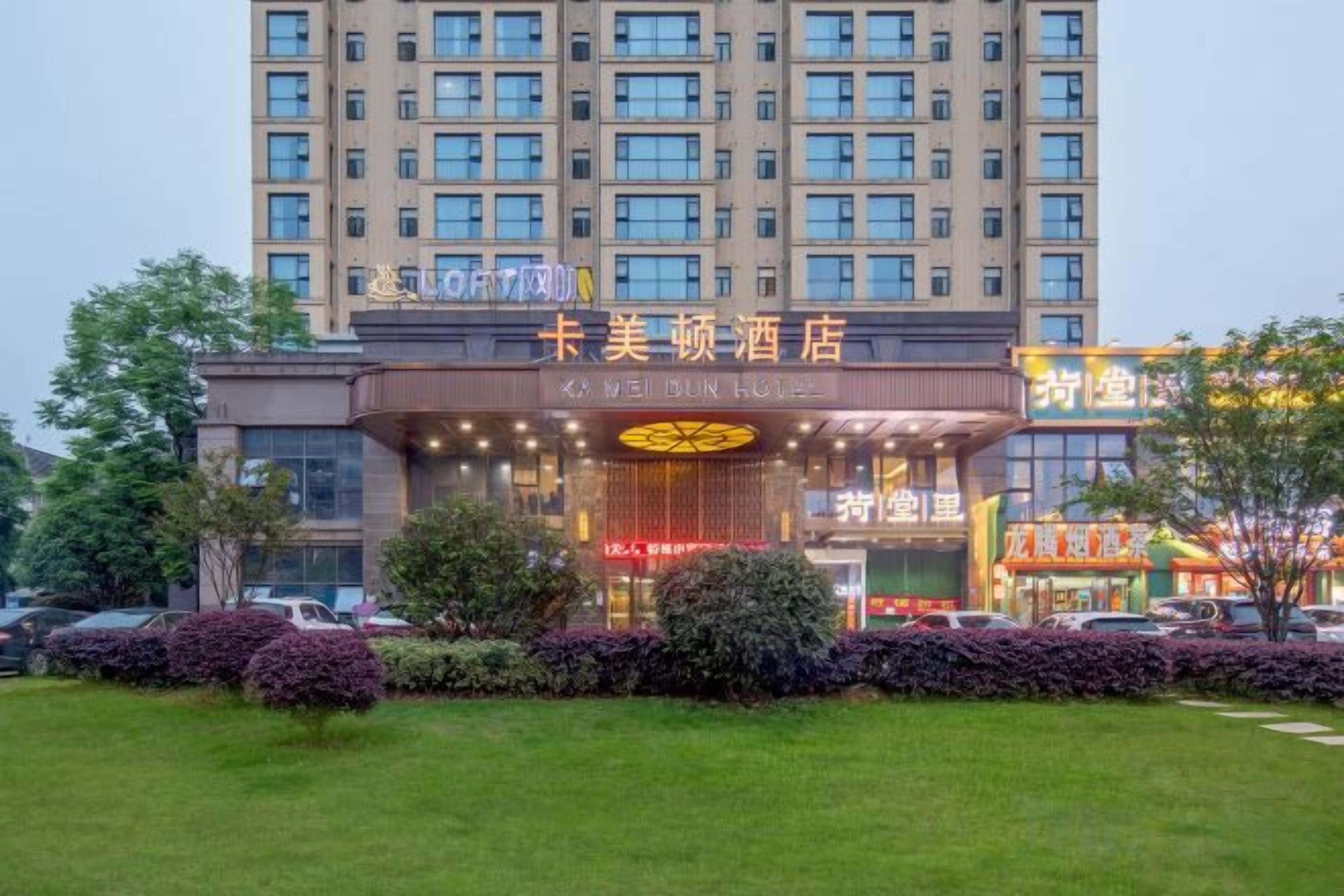 A hotel with a prominent entrance, multiple floors, and a well-maintained lawn.