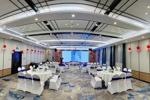 A conference room with round tables, white chairs, and a large screen at the front. - Kameidun Hotel (Changsha University of Science and Technology Yuntang Campus) (Changsha)