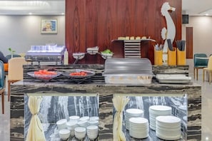 A buffet setup with various food items and a counter with plates and bowls. - Kameidun Hotel (Changsha University of Science and Technology Yuntang Campus) (Changsha)
