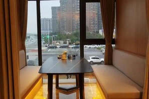 A room with a window view of a cityscape, a table, and a bench. - Kameidun Hotel (Changsha University of Science and Technology Yuntang Campus) (Changsha)