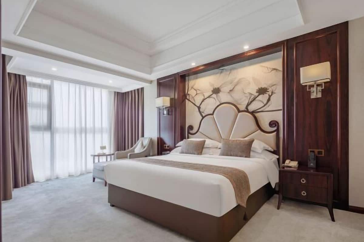 A hotel room with a large bed, a nightstand, a chair, and a view of the outdoors.