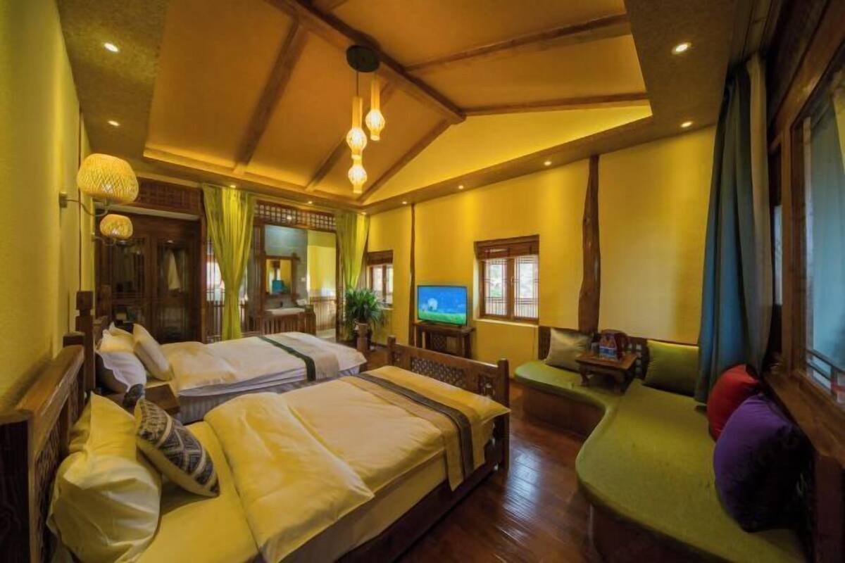 A hotel room with two beds, a television, a sofa, and a small table.