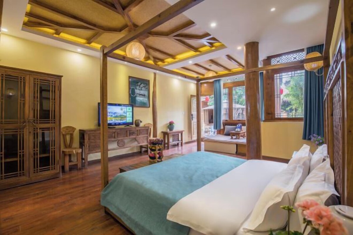 A traditional-style bedroom with a bed, wooden furniture, and a television.