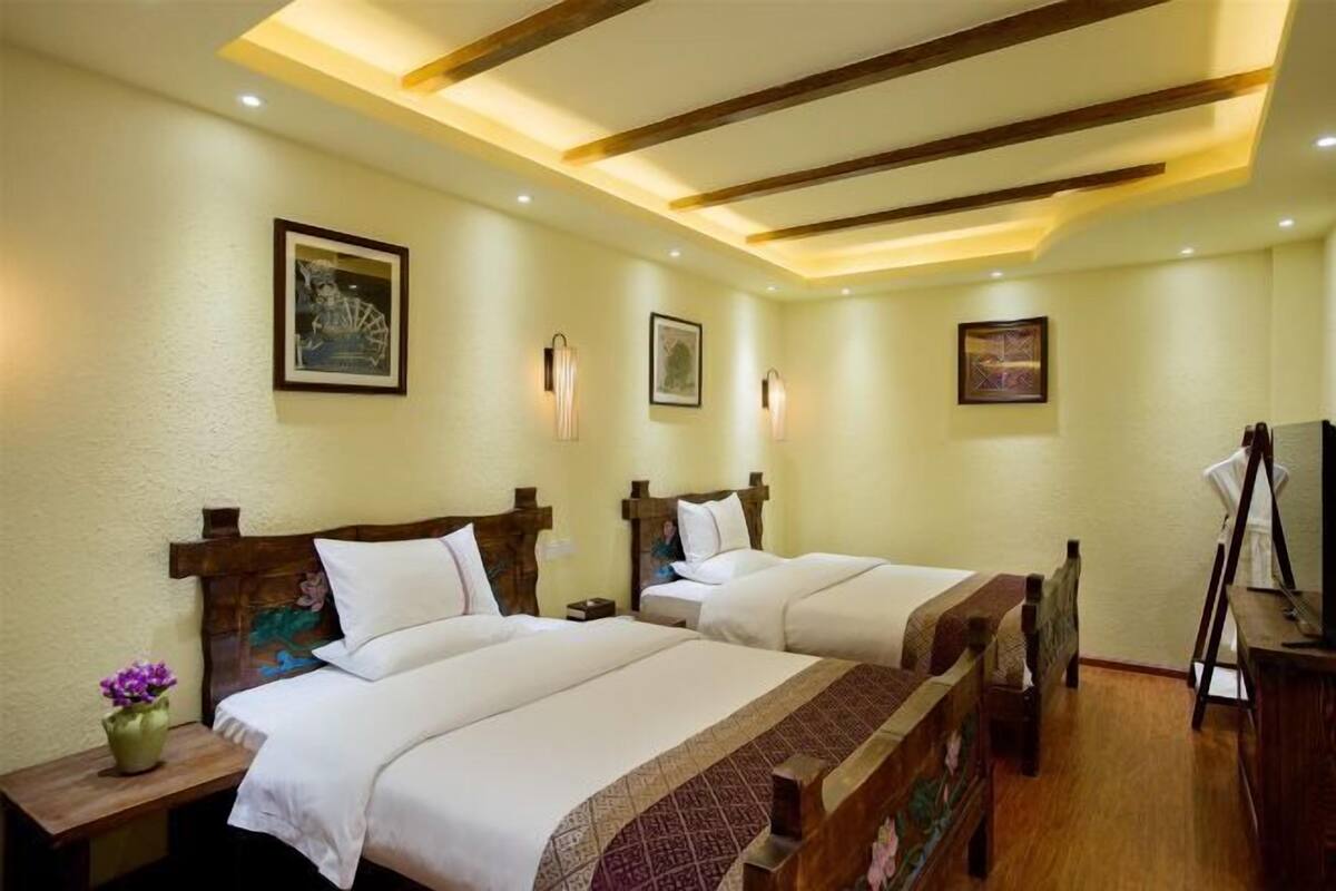 A hotel room with two beds, wooden headboards, and a ceiling with exposed beams.