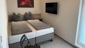 Una camera da letto con due letti, una TV, un quadro e una sedia.