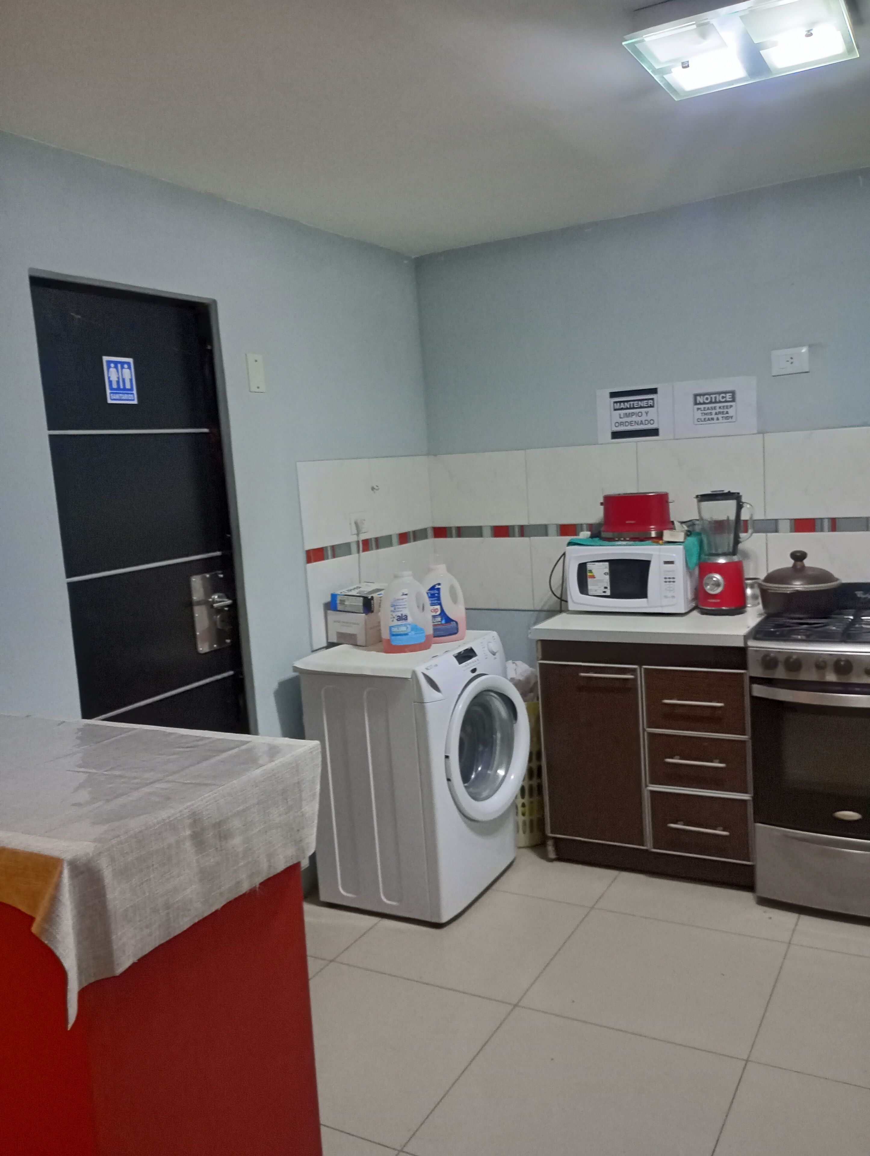 A compact kitchen with a washing machine, microwave, stove, and cabinets.