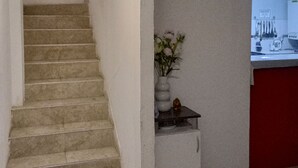 A staircase leading to a landing with a small table holding a vase of flowers. - Ushuaia hostal  (Ushuaia)