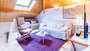 Ein gemütliches Schlafzimmer im Dachgeschoss mit schrägverdeckter Decke, einem großen Fenster, einem Bett, einem Schreibtisch und einer Karte an der Wand.