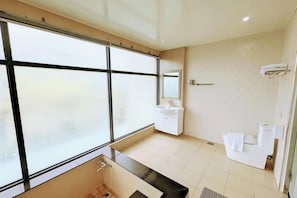 Un baño moderno con un ventanal grande, un lavabo, un espejo y una zona de ducha.