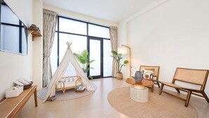 A room with a large window, a bed, a chair, a lamp, and a small tent-like structure. - Rainbow Mansion (Taitung)