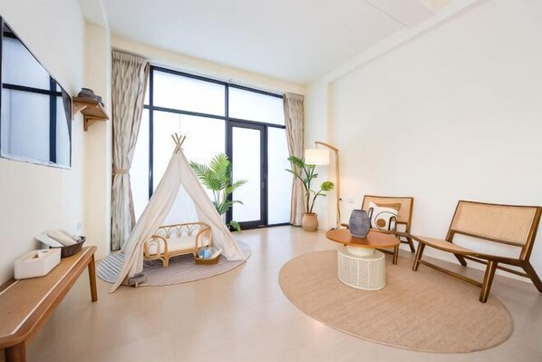 A room with a large window, a bed, a chair, a lamp, and a small tent-like structure. - Rainbow Mansion (Taitung)