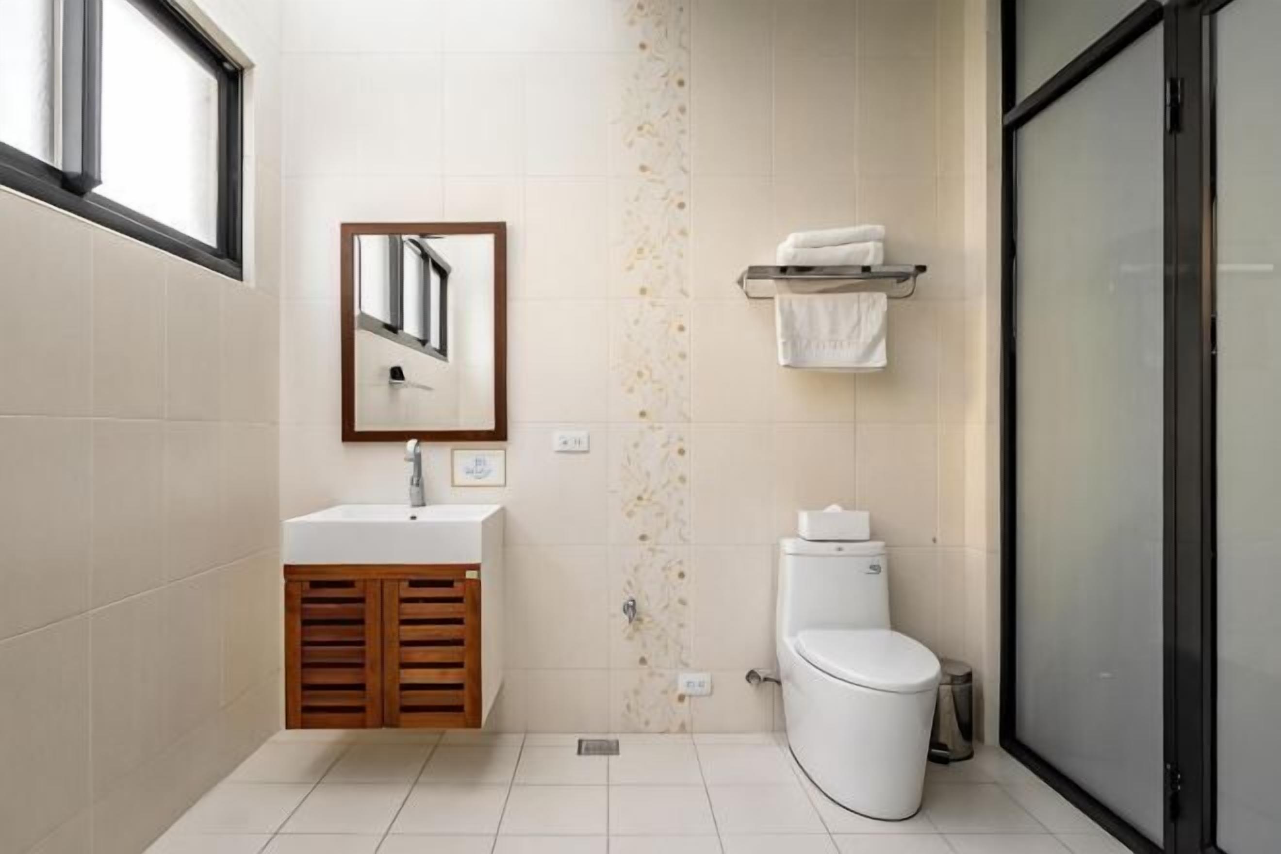 A bathroom with a sink, mirror, toilet, and a towel rack.