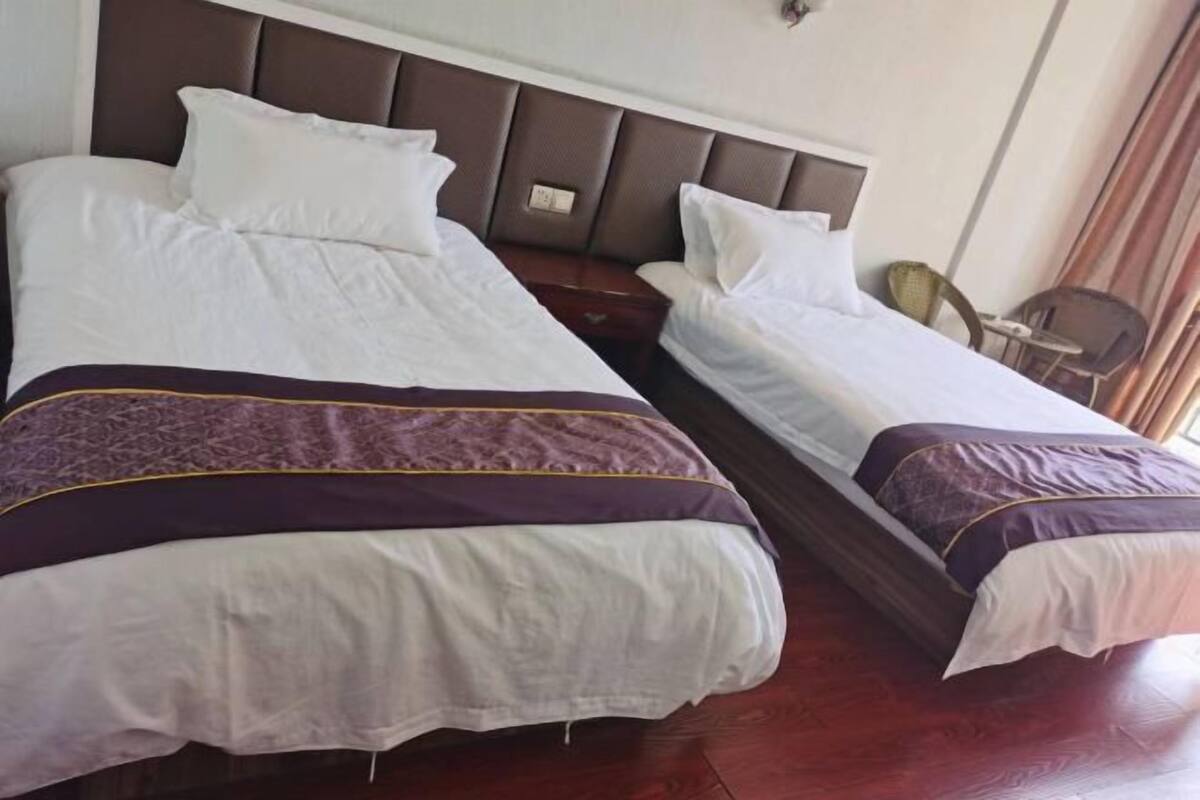 A hotel room with two beds, each with white bedding and a brown headboard.