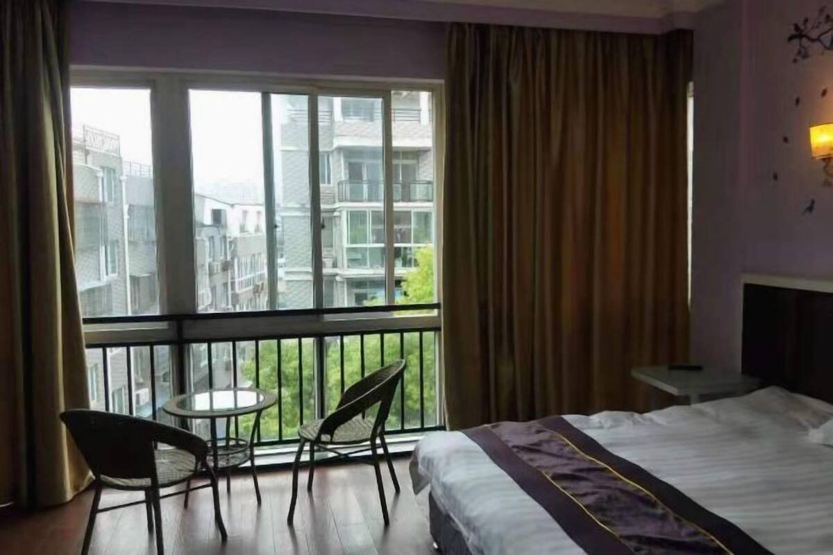 A hotel room with a balcony, a bed, a small table, and two chairs.