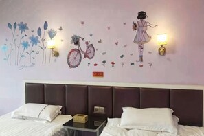 Habitación de hotel con una cama, dos mesitas de noche y una pared decorada con arte que incluye flores, una bicicleta y una niña.