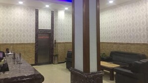 A reception area with a marble counter, a black leather sofa, and a wooden pillar. - Xianju Tianyuan Hotel (Xianju)