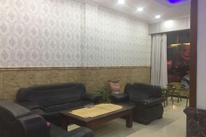 Habitació amb paper pintat de disseny, un sofà negre, una taula de centre de fusta i un separador de vidre amb vista.