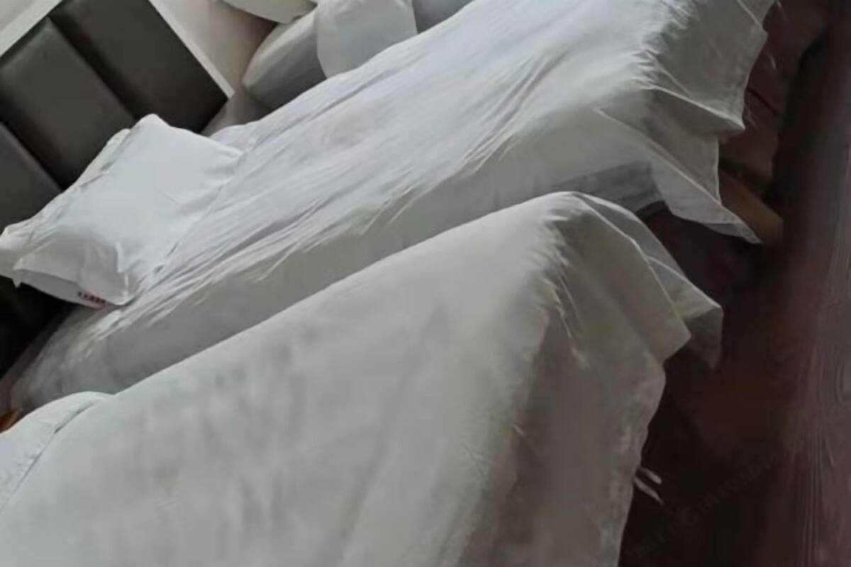 A bed with white linens and a dark headboard.