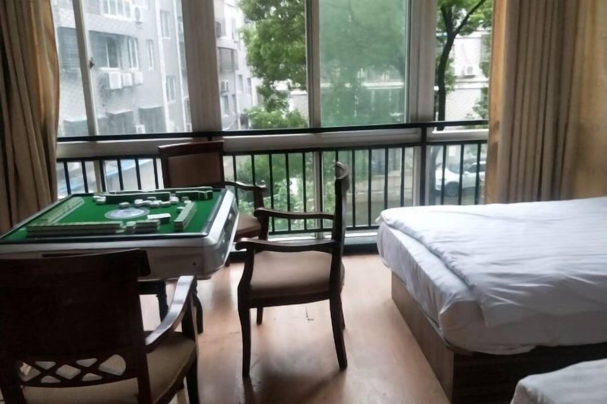 A hotel room with a pool table, a bed, and a view of the city through large windows.