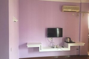 A room with a flat-screen TV mounted on a wall, a white shelf below it, and an air conditioning unit on the wall. - Xianju Tianyuan Hotel (Xianju)