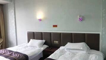 Habitación de hotel con dos camas, cabecero e iluminación empotrada en la pared.