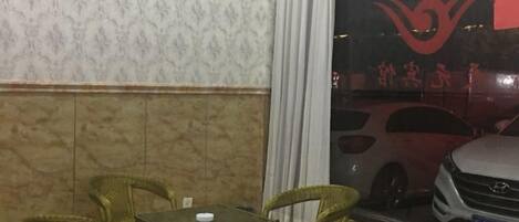 Una habitación con pared estampada, una mesa con sillas y una ventana que refleja un coche.