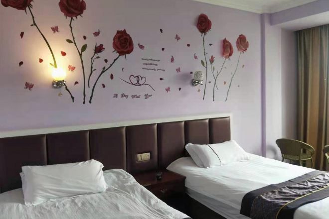 Habitación de hotel con dos camas, cabecera, decoración floral en la pared y una mesita de noche.