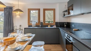 Una cucina moderna con mobili scuri, un piano di lavoro in legno e un'area pranzo apparecchiata per un pasto.