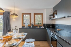 A modern kitchen with dark cabinetry, a wooden countertop, and a dining area set for a meal.