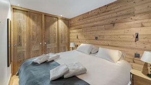 Una camera da letto con un letto grande, pareti in legno, due comodini con lampade e un armadio.