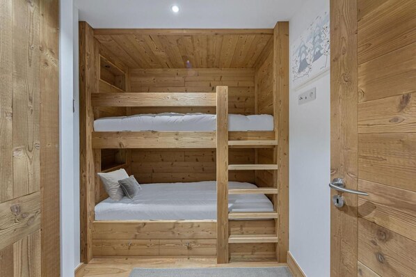 A bunk bed room with wooden walls and a metal ladder.