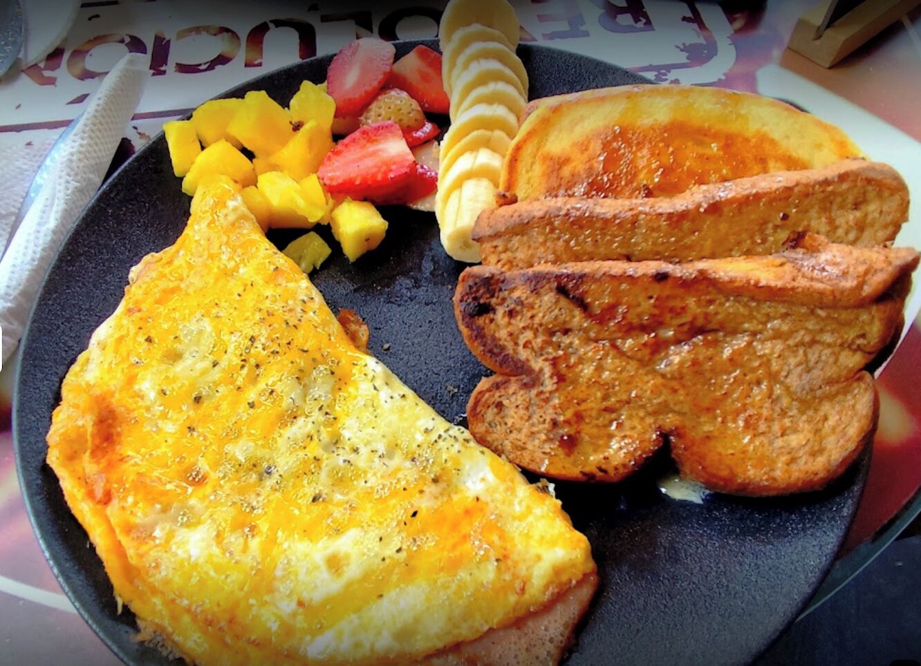 Um prato com ovo frito, torrada e fruta.