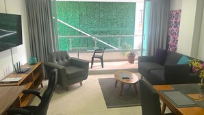 Una sala moderna con balcón, un sofá, una mesita de centro y un televisor.