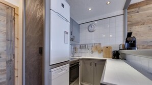 A compact kitchen with white appliances, a wooden door, and a tiled backsplash. - 2nd floor, balcony, tv, ski locker, 41m², Tignes (Tignes)