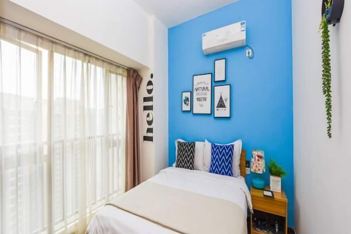 Quarto com cama, mesa de cabeceira, ar condicionado fixado na parede e quadros emoldurados.