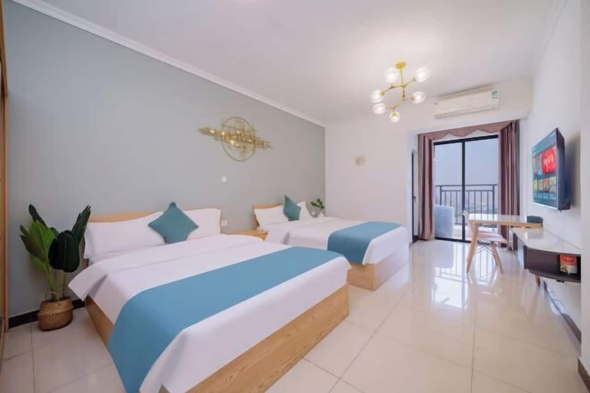 Quarto de hotel com duas camas, uma mesa de jantar, televisão e varanda.