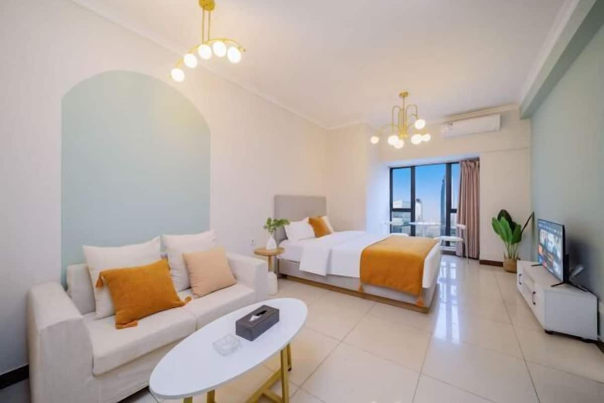 Quarto de hotel moderno com sofá, cama, televisão e mesa de jantar.