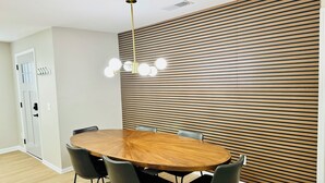 A modern dining area with a round wooden table, black chairs, and a unique ceiling light fixture. - Modern Brick Ranch Retreat NEW Renovation (Mableton)
