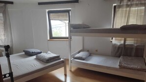 A dormitory room with bunk beds, a window with blinds, and a wooden floor. - Budget Rooms (Sarajevo)