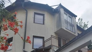 A two-story house with a wooden door, a balcony, and a garage. - Budget Rooms (Sarajevo)